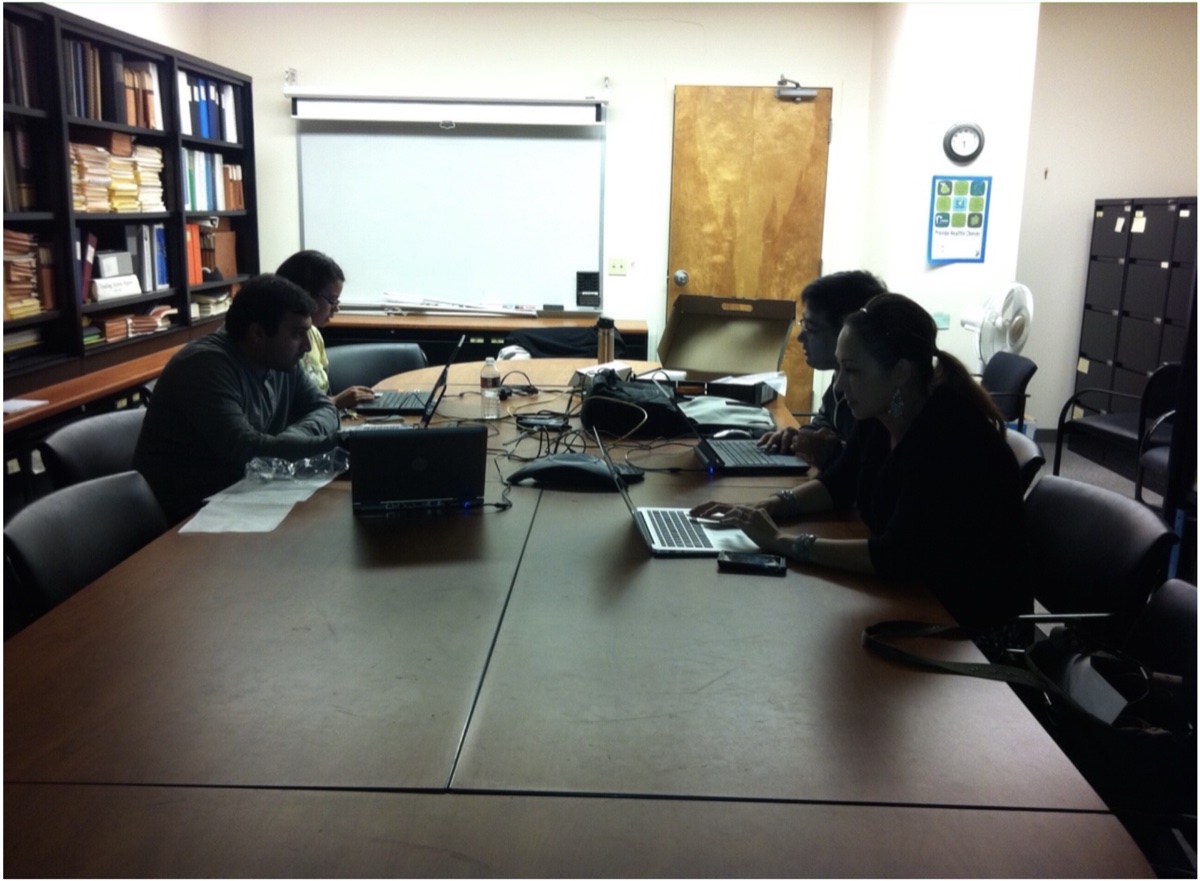 Conference room photo of team members hunched over laptops at a long table.
