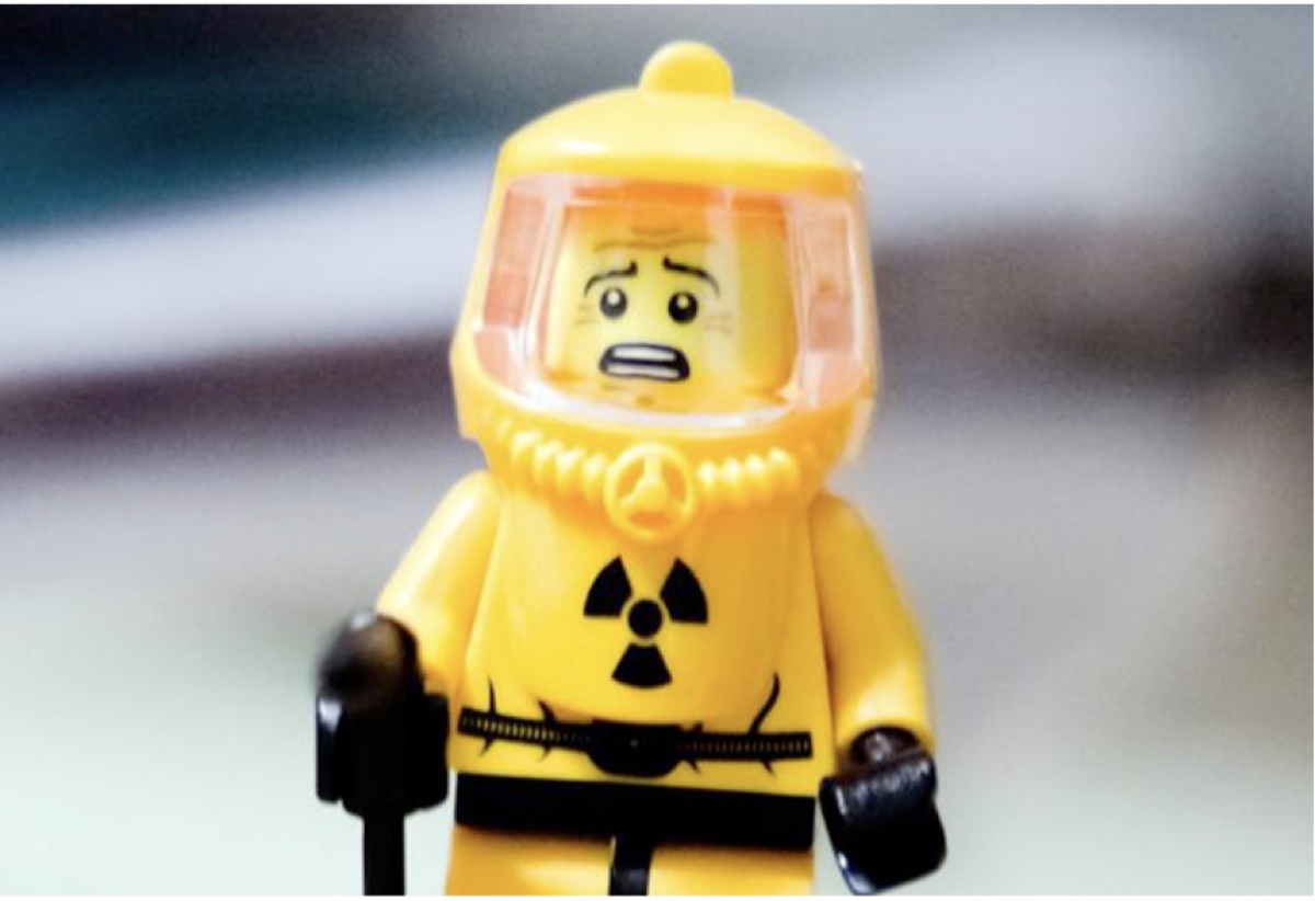 A Lego figure in a yellow hazmat suit looking alarmed.